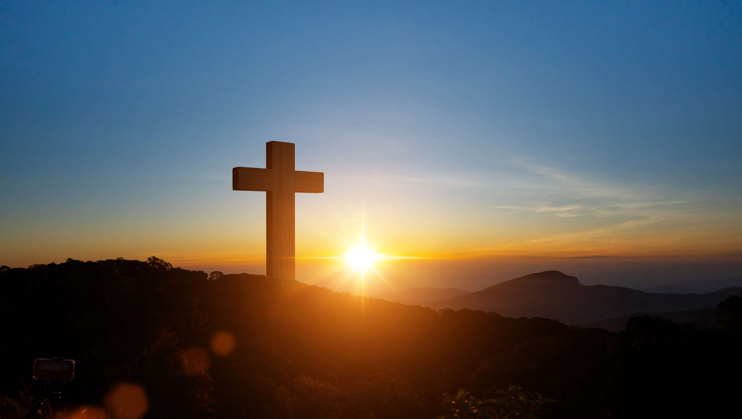 Silhouettes of Christian cross symbol on top mountain at sunrise